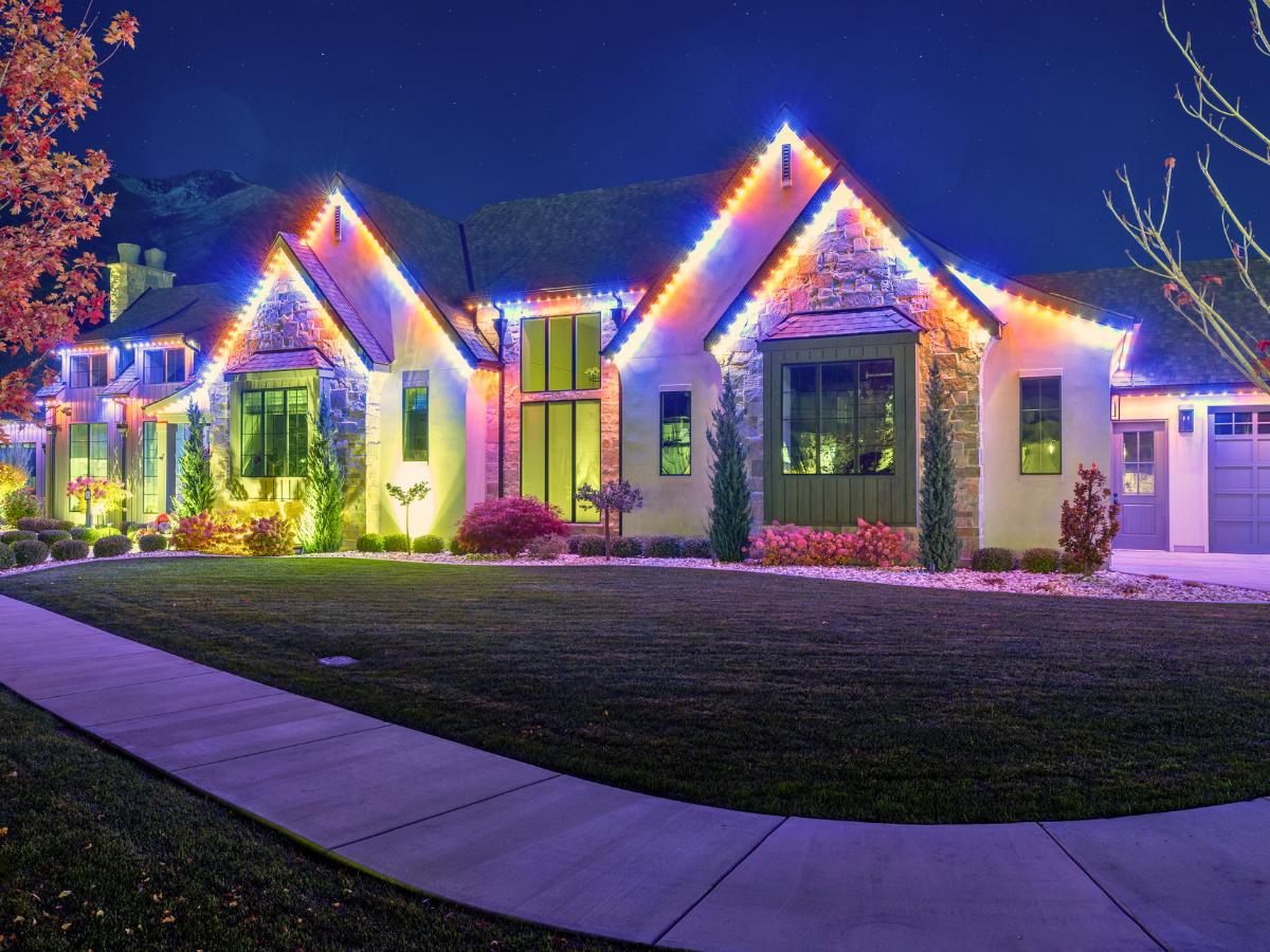Multicolor permanent LED trim lights on a stone ranch home